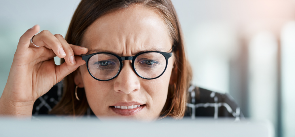 kommunikationsmissar ett vanligt problem på svenska företag.

En kvinna sitter nära en datorskärm och lutar sig lätt framåt. Hon har brunt axellångt hår, bär mörka glasögon och rynkar pannan i koncentration. Med ena handen håller hon i kanten av glasögonen, som om hon försöker fokusera eller förstå något på skärmen. Hennes blick är riktad nedåt mot datorn och ansiktsuttrycket signalerar eftertanke och ansträngning. Bakgrunden är mjuk och ljus, vilket sätter fokus på hennes ansikte och reaktion.