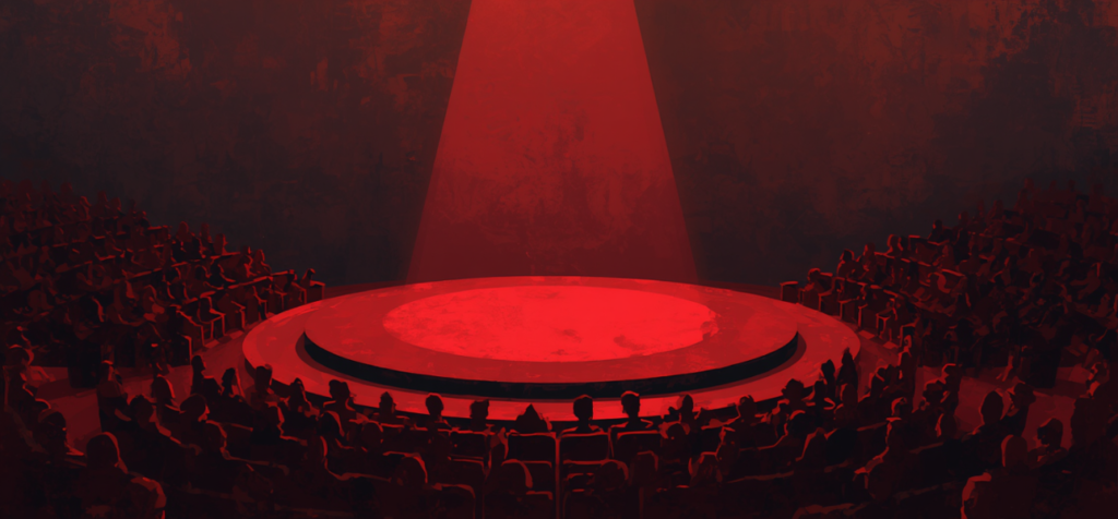 En upplyst röd scen i ett mörkt auditorium med publik runtom. Bilden förmedlar känslan av ett stort scenframträdande, fokus, närvaro och talarens möte med publiken.